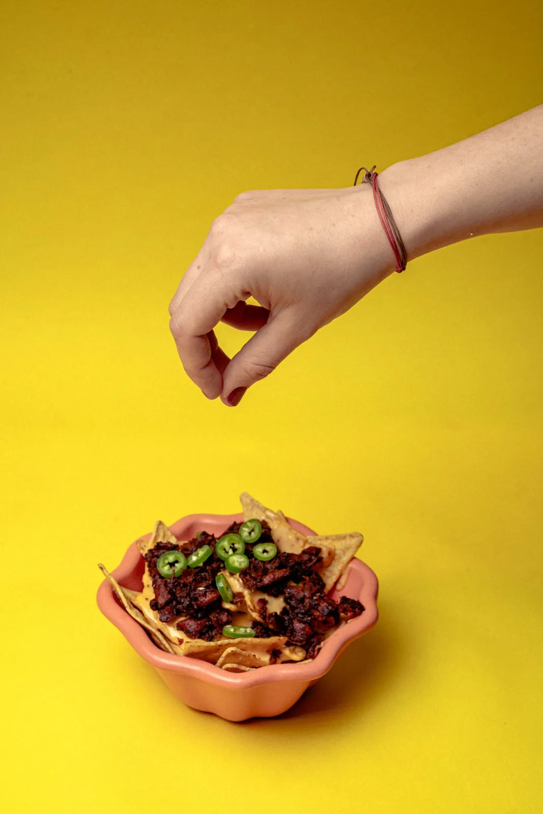 Nachos con Chorizeta, queso fundido y rodajas de jalapeño en un tazón rosa