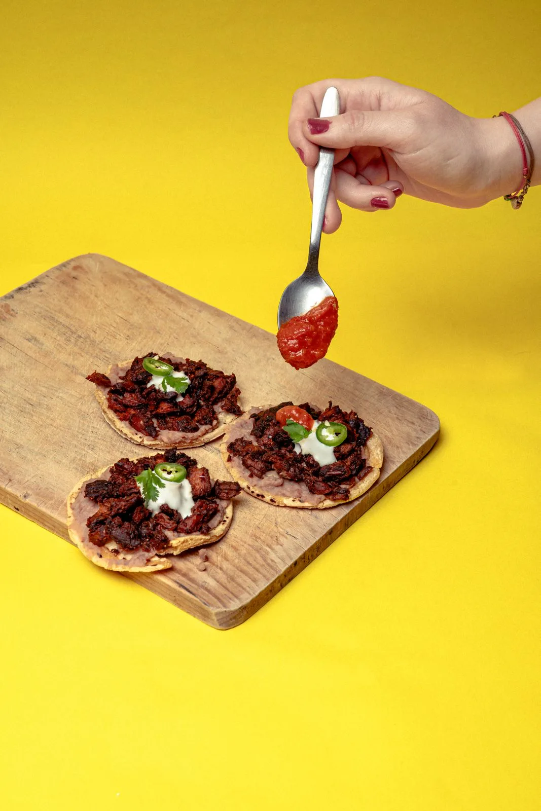 Tres tostadas de Chorizeta con crema y jalapeño sobre una tabla de madera